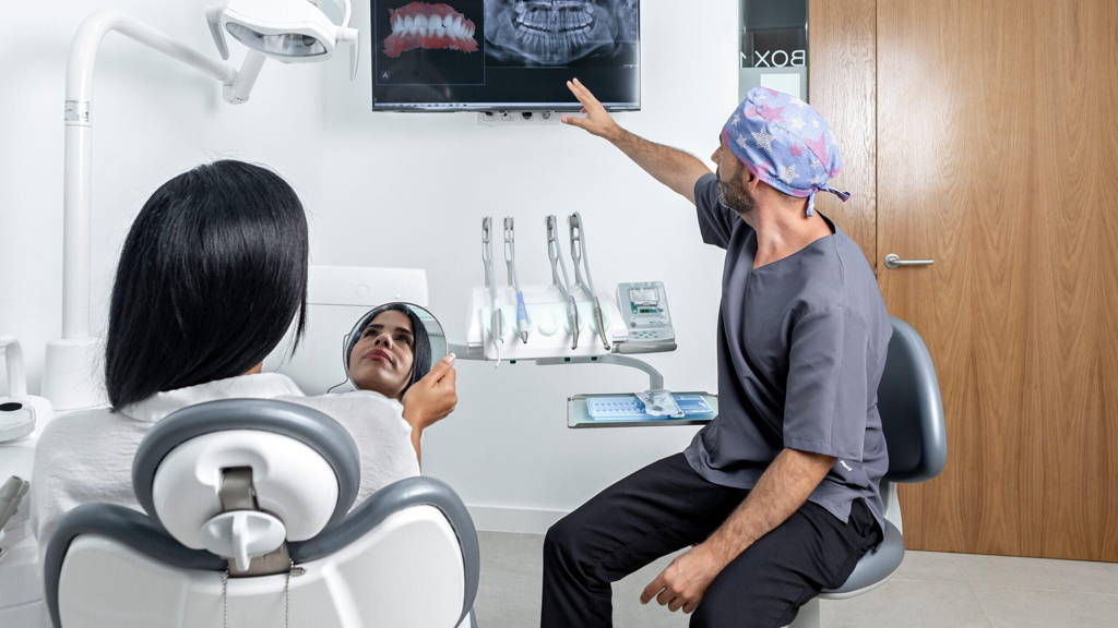 Dentist showing a x-ray to a patinet that is sitting on a chair in a clinic