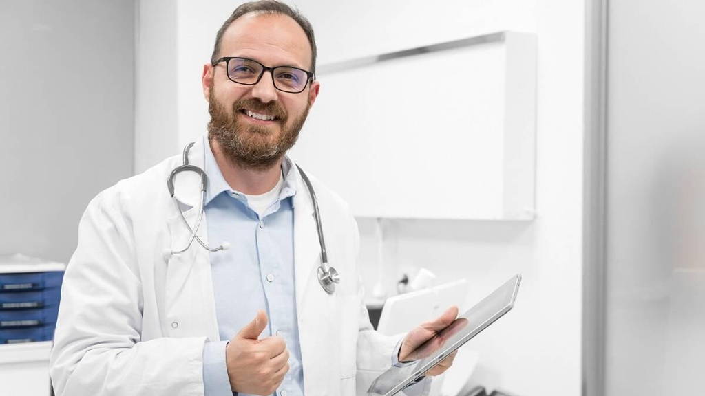 Friendly male doctor smiling and giving thumb up sign