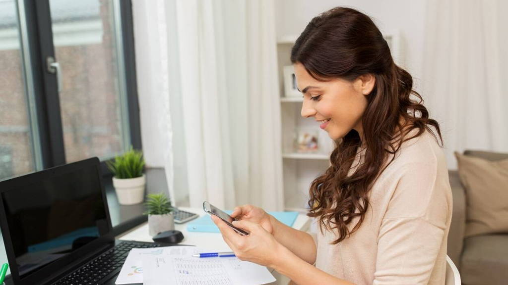 woman with papers and smartphone working at home