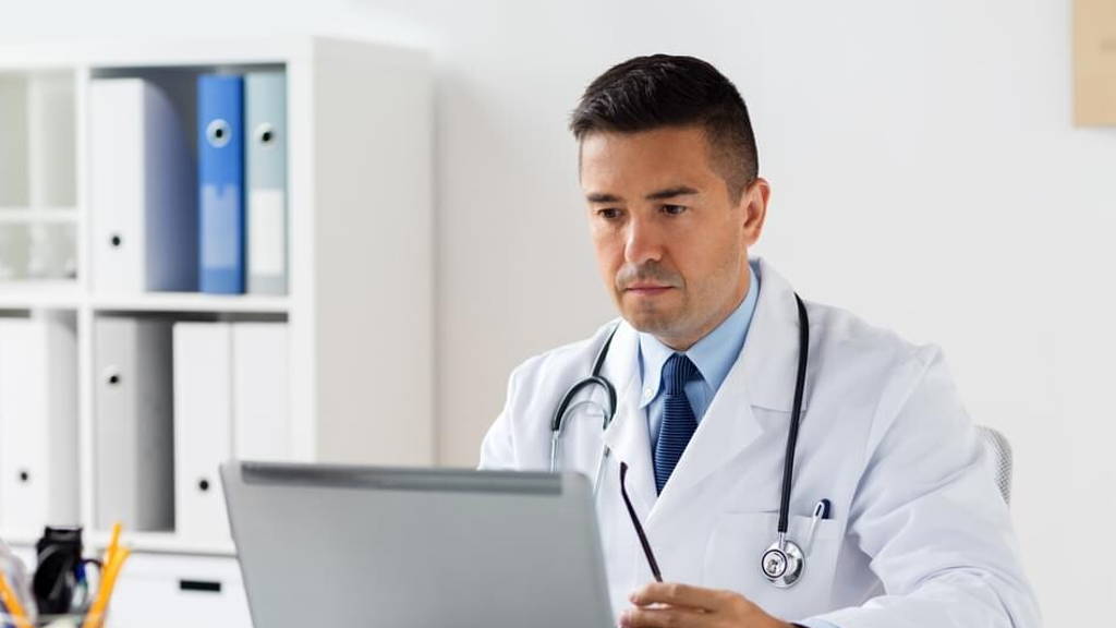 male doctor in white coat with laptop at hospital