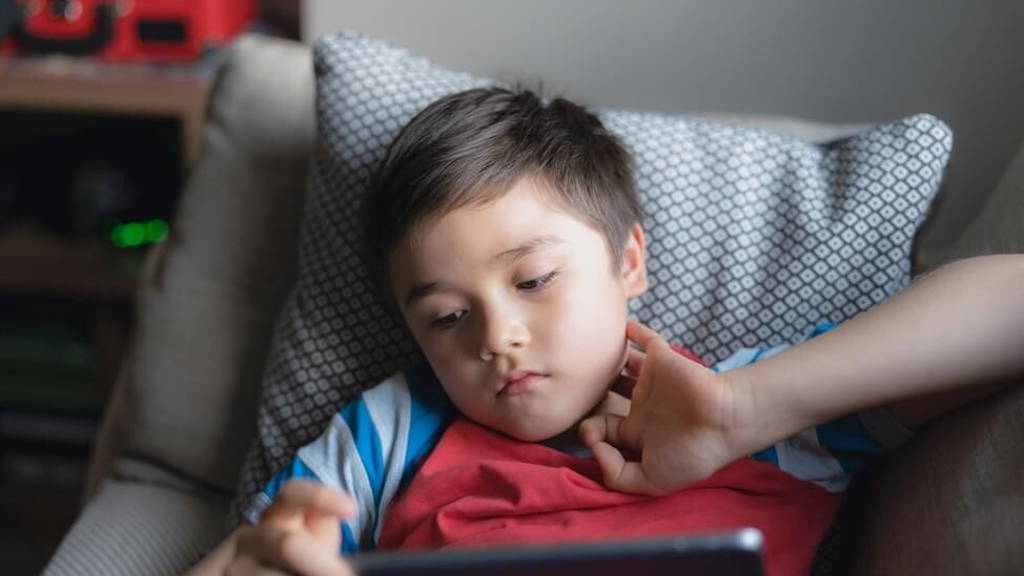 Young boy holding tablet looking out deep in thought, Unhappy ki