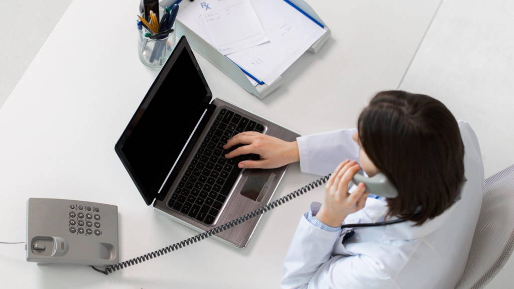 doctor with laptop calling on phone at clinic