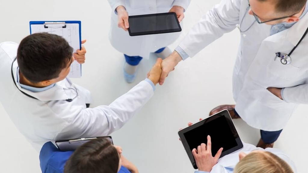 doctors with tablet pc doing handshake at hospital