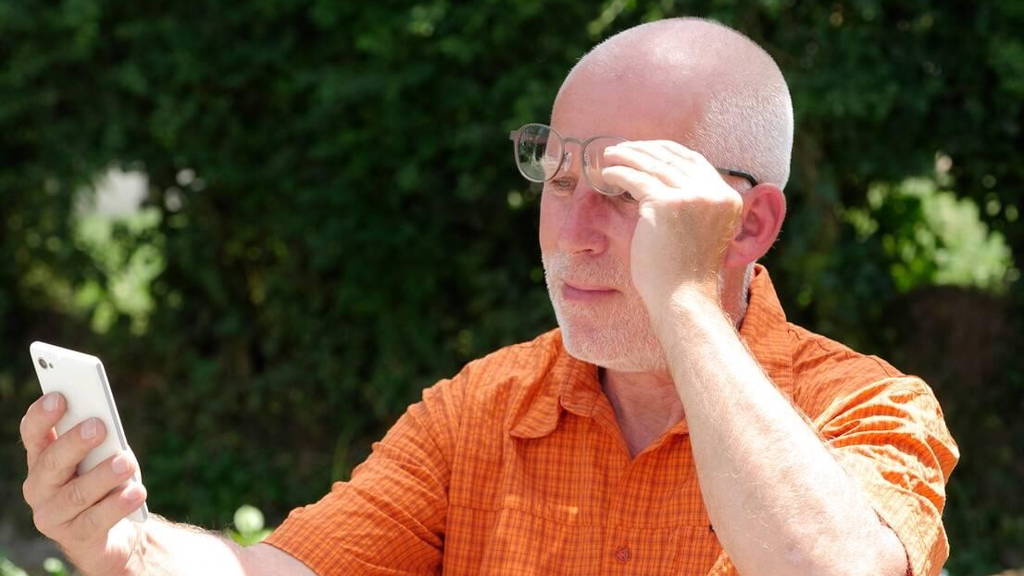 mature man has problems with his eyesight for reading on his sma