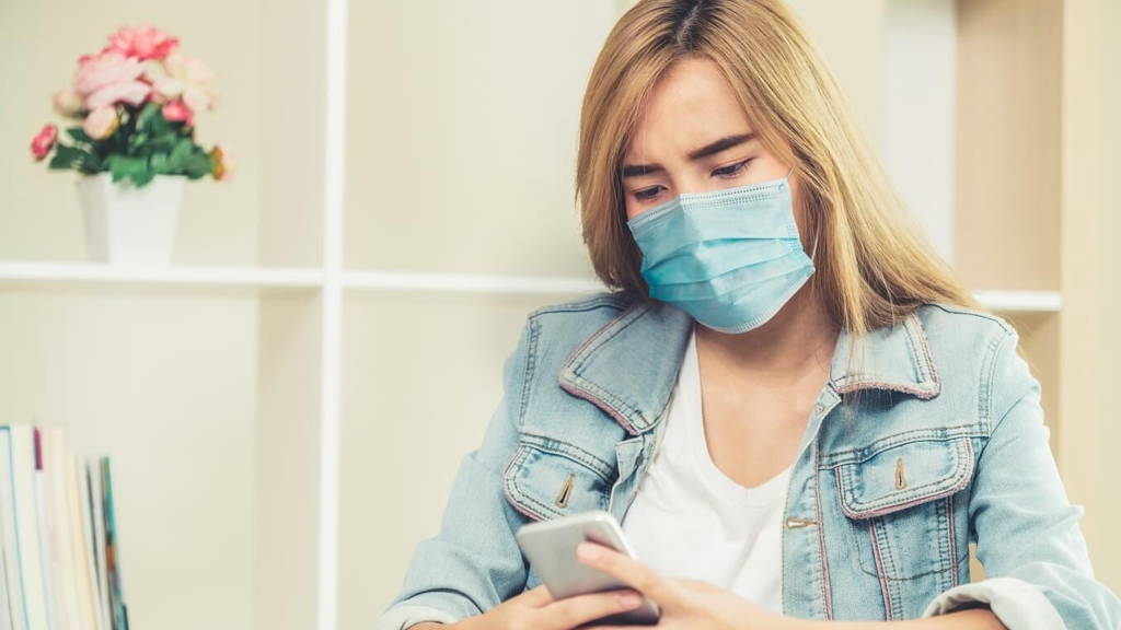 Quarantined woman working at home wearing face mask protect from Coronavirus.