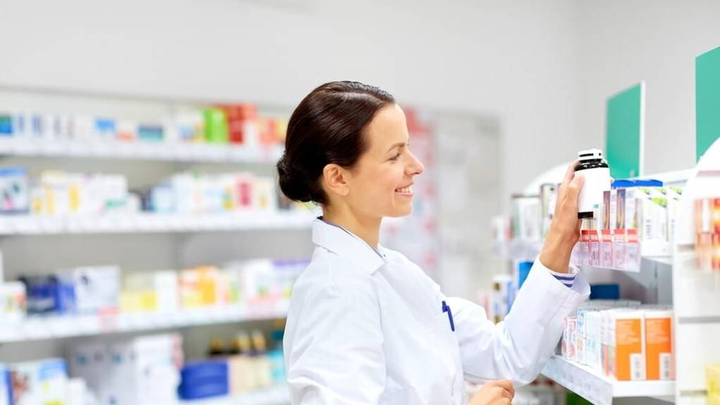 happy female apothecary with drug at pharmacy